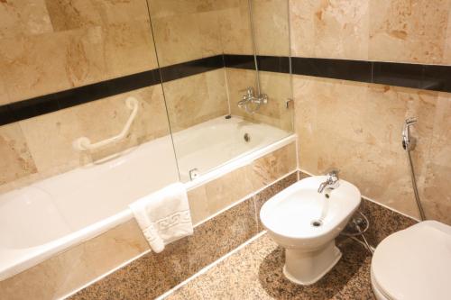 فندق هابي دايز في المنامة: حمام مع مرحاض وحوض استحمام ومغسلة