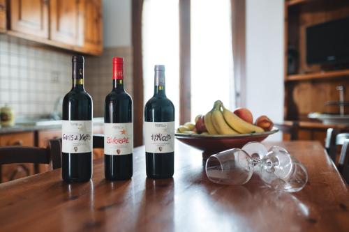 two bottles of wine sitting on a table with a bowl of fruit at Agriturismo Podere Ristella - Wine&Food in Montemassi