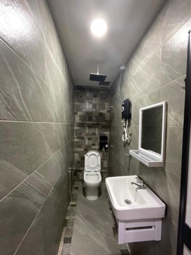 a bathroom with a toilet and a sink and a mirror at The Sky Inn in Kuantan