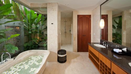 a bathroom with a tub and a large plant at Villa Joss Seminyak by Nagisa Bali in Seminyak