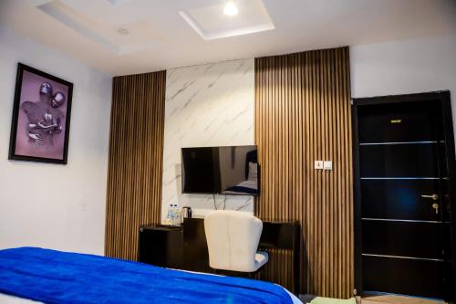 - une chambre avec un lit bleu et une chaise blanche dans l'établissement El Elyon Hotel and Suites, à Lagos