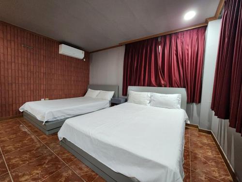 two beds in a hotel room with red curtains at Busan Station Centum Hotel in Busan