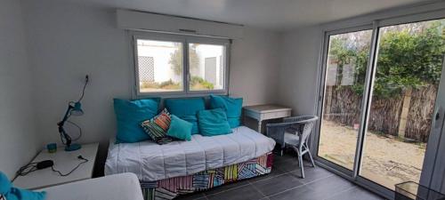 ein Schlafzimmer mit einem Bett mit blauen Kissen und einem Fenster in der Unterkunft La Nantaise de la mer in Saint-Hilaire-de-Riez