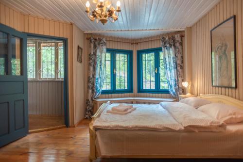 a bedroom with a bed and windows and a chandelier at Villa Sara in Sinaia near Peles & Gondola in Sinaia