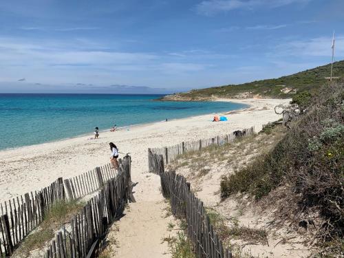 a sandy beach with a wooden fence and the ocean at T2 clim 54m2, 17m2 de terrasse très belle vue mer in LʼÎle-Rousse