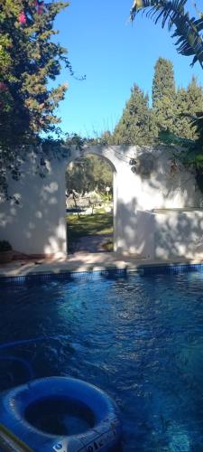 a swimming pool with an archway in the water at Les Sons du Jardin Monastir in Monastir