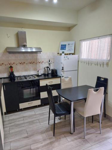 uma cozinha com uma mesa preta, cadeiras e um fogão em Rodica Apartment em Sibiu