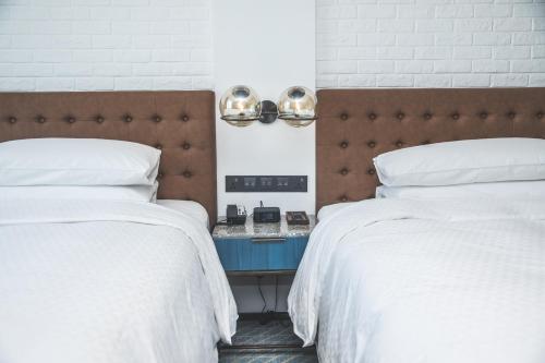 a bedroom with two beds with white sheets and a headboard at Four Points by Sheraton Shanghai Hongqiao in Shanghai