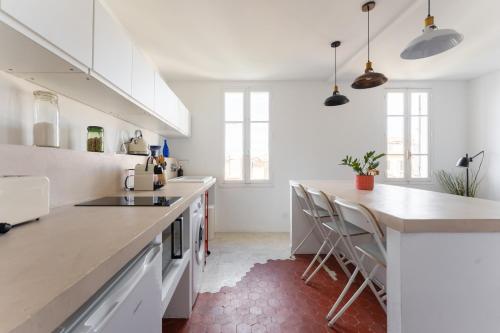 une cuisine avec des armoires blanches et un comptoir avec des tabourets dans l'établissement Paisible cocon au cœur du 7eme, à Marseille