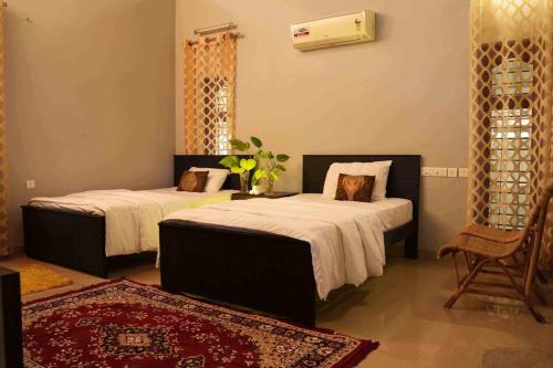 a bedroom with two beds and a chair at Bellevue Homestay - Ayurvedic Wellness Centre in Kozhikode