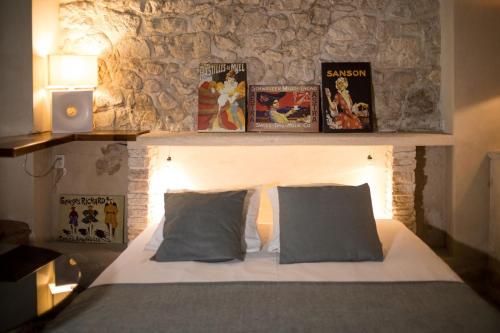 a bedroom with a bed with two pillows and a stone wall at In Provence Hôtel - Expérience Authentique in Venelles