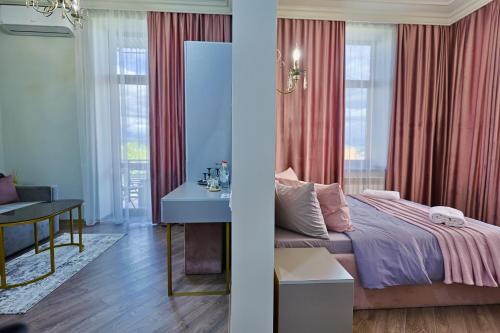 a bedroom with a bed and a desk and windows at Fiorella Gyumri in Gyumri