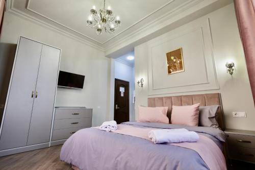 a bedroom with a bed with pink sheets and a chandelier at Fiorella Gyumri in Gyumri