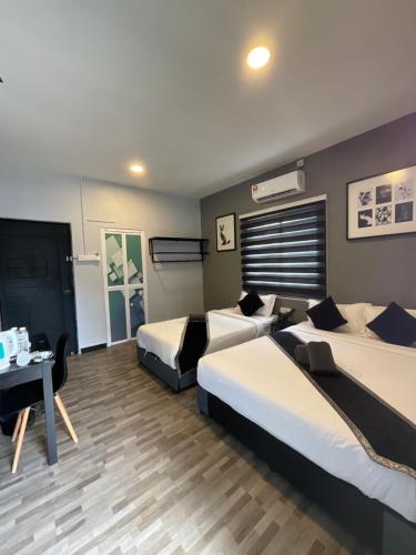 a hotel room with two beds and a table at The Sky Inn in Kuantan
