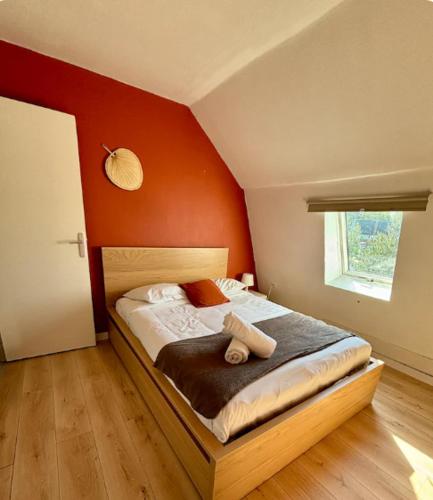 ein Schlafzimmer mit einem Bett mit einer orangefarbenen Wand in der Unterkunft Maison Saint Roch in Tourcoing