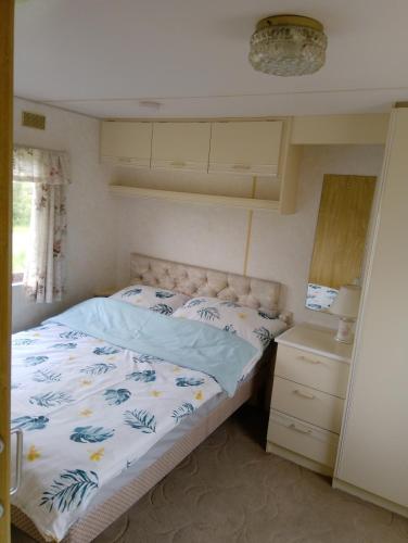 a bedroom with a bed with a blue and white comforter at Domek za świerkami in Charzykowy