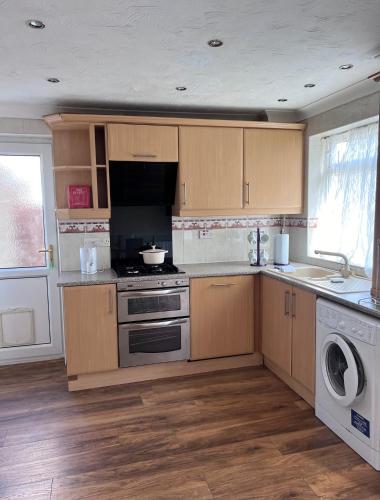 a kitchen with wooden cabinets and a stove top oven at Newport Pagnell Guest House in Buckinghamshire
