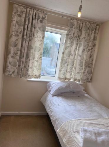 a bedroom with a bed and a window with curtains at Newport Pagnell Guest House in Buckinghamshire