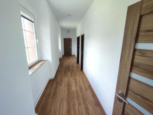 a hallway with a wooden floor and a window at Zámeček Čeřov in Jičín