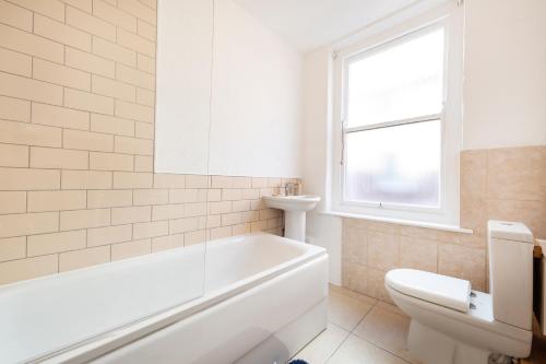 a white bathroom with a tub and a toilet at Stunning 5-Bed Maisonette in Bristol in Bristol