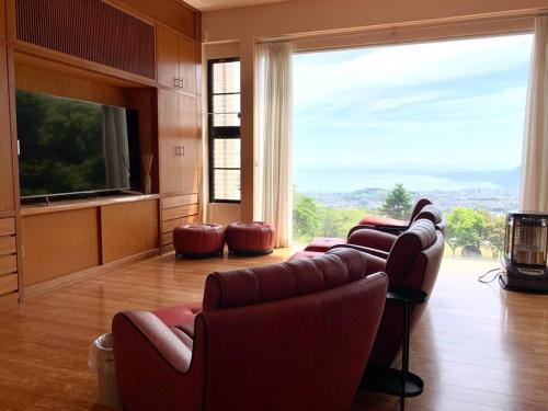 a living room with couches and a large window at Manden in Beppu