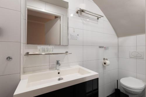 a white bathroom with a sink and a toilet at Midtown Hotel Triple Room in Amsterdam