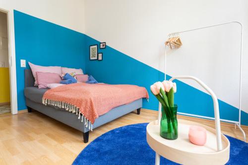 Cette chambre comprend un lit et une table avec un vase de fleurs. dans l'établissement FullHouse - Halle - Paulus Apartment - Nespresso, à Halle-sur-Saale