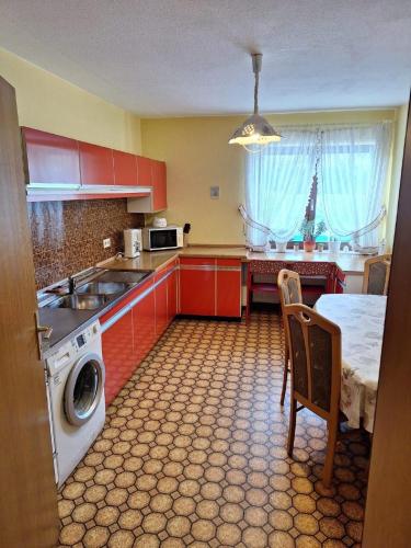 a kitchen with red cabinets and a sink and a table at Ferienwohnung Marianne Simon in Tann