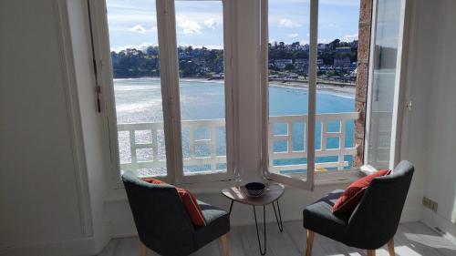 une chambre avec deux chaises, une table et des fenêtres dans l'établissement Splendide vue mer studio, à Perros-Guirec