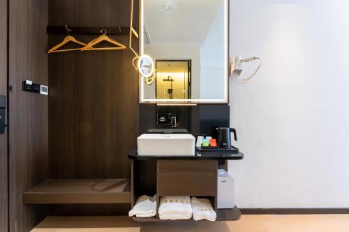 La salle de bains est pourvue d'un lavabo et d'un miroir. dans l'établissement Shanghai Pudong Xiangguo Hotel, à Shanghai