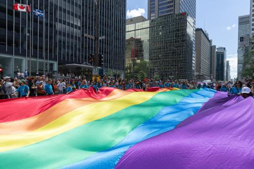 una gran bandera arco iris frente a una multitud de personas en Alt Hostel, en Montreal