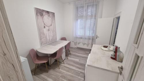 a white kitchen with a table and chairs and a counter at Apartman Centrum Mudronova in Košice