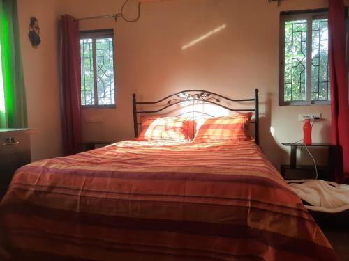a bed in a bedroom with two windows at Meghamala Bed and Breakfast in Kolthare