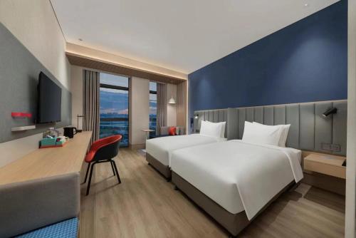 長春市にあるHoliday Inn Express Changchun Ecological Square, an IHG Hotelの白いベッドと青い壁が備わるホテルルームです。