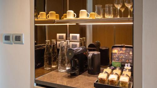 a counter with a coffee maker and glasses on it at Chatrium Grand Bangkok in Bangkok