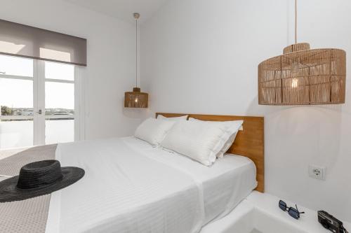 a white bedroom with a bed with a hat on it at Soley Naxos in Naxos Chora