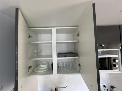 La salle de bains est pourvue d'étagères blanches et de toilettes. dans l'établissement Tranquillité près de Disney: Studio Cozy à Meaux, à Meaux