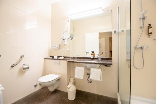 a bathroom with a toilet and a sink and a shower at Hotel Wehrburg in Cuxhaven
