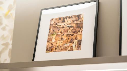 a picture frame on a shelf with a painting of buildings at Amatera Luxury Apartments in Matera