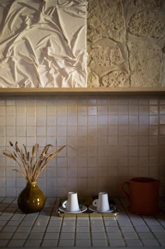 two plates with cups and a vase on a tiled counter at In Provence Hôtel - Expérience Authentique in Venelles