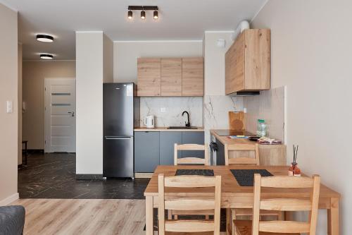 cocina con mesa de madera y nevera en Poznań Airport Homely Apartment, en Poznan