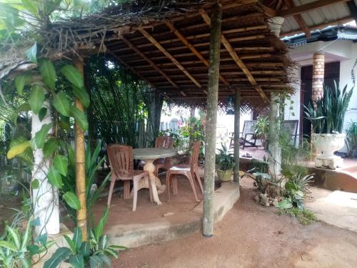 a patio with a table and chairs under a pergola at Mystay in Mawanella