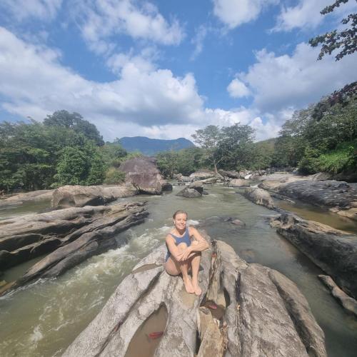 a man sitting on a rock in a river at Mystay in Mawanella