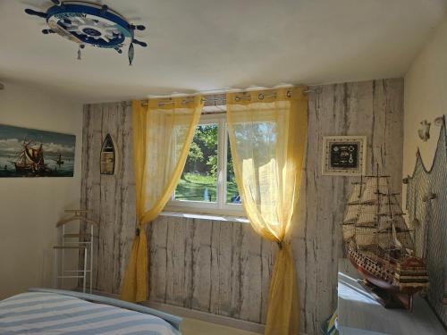 une chambre avec une fenêtre avec un bateau pirate sur le mur dans l'établissement Appart à la campagne, à Perpezac-le-Noir