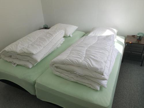 two beds with white blankets and pillows on them at Feriestedet Skovly in Klemensker