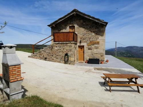 a stone building with a picnic table and a bench at Villa Brenagudina - Cabaña Pasiega con piscina climatizada in San Pedro del Romeral