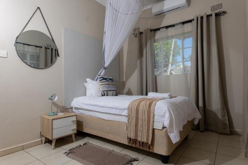 1 dormitorio con cama con espejo y ventana en Hungwe House en Victoria Falls