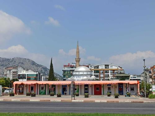 a building in a city with a mosque in the background at NEXT TO CAFES, BEACH AND ALL AMENITIES in Antalya