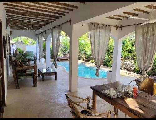 a living room with a table and a swimming pool at Namayani apartment in Pwani Mchangani