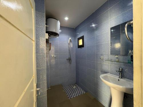 a blue tiled bathroom with a sink and a shower at Studio Villa Hortensia in Dakar